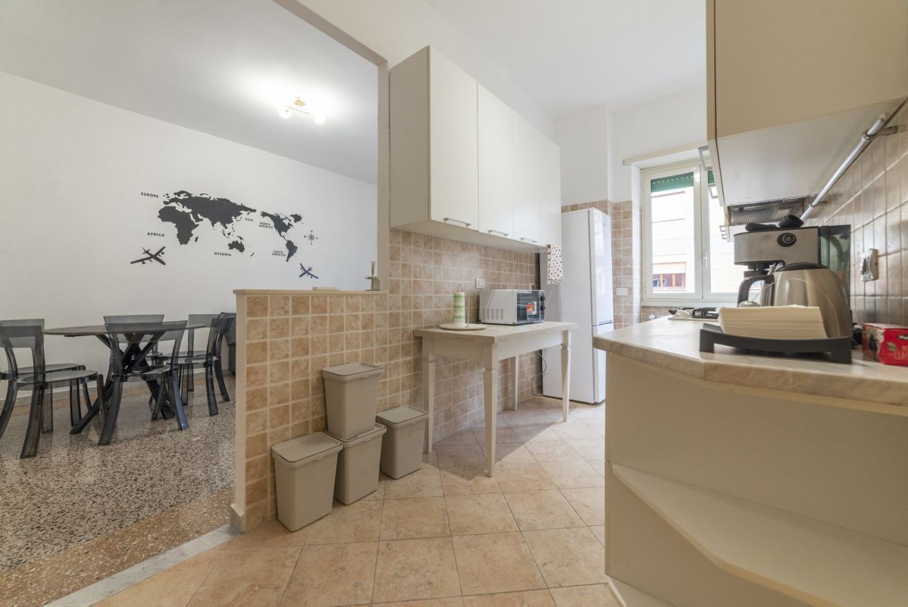A compact kitchen with a dining area, a world map on the wall, and a coffee machine.
