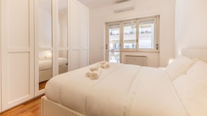 Un dormitorio con una cama grande, un armario y una ventana con vistas a balcones.
