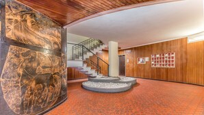 Un vestíbulo con pared de madera, una escalera y un suelo estampado.