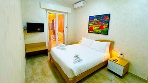 A hotel room with a bed, a bedside table, a TV mounted on the wall, and a painting above the bed. - La Palmetta (Near Metro A) (Roma)