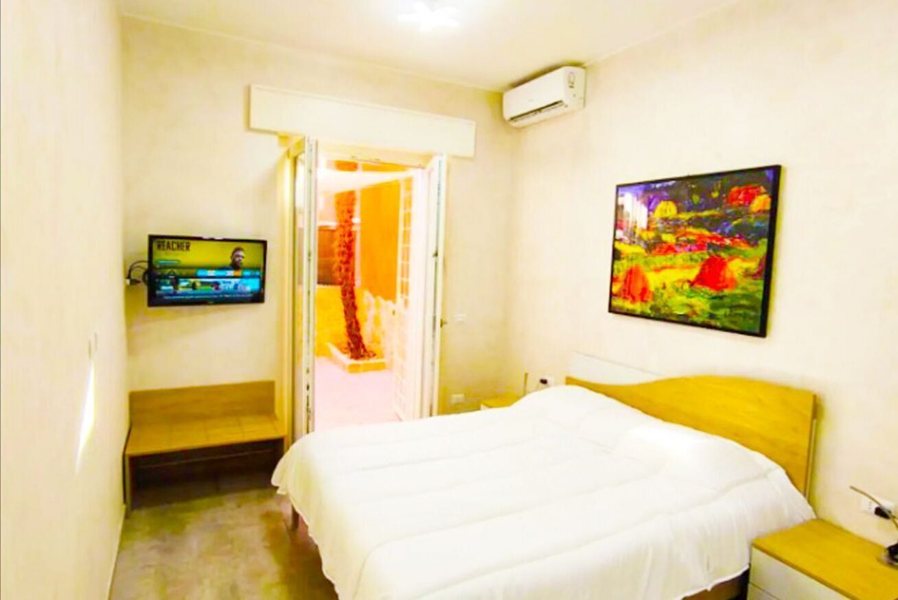 Een hotelkamer met een bed, een televisie, een schilderij en een airconditioner.