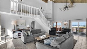 A spacious living area with a grey sofa set, a coffee table, and a staircase leading to an upper level.
