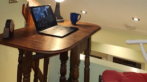 A room with a skylight, a wooden table with a laptop, a lamp, and a blue mug.