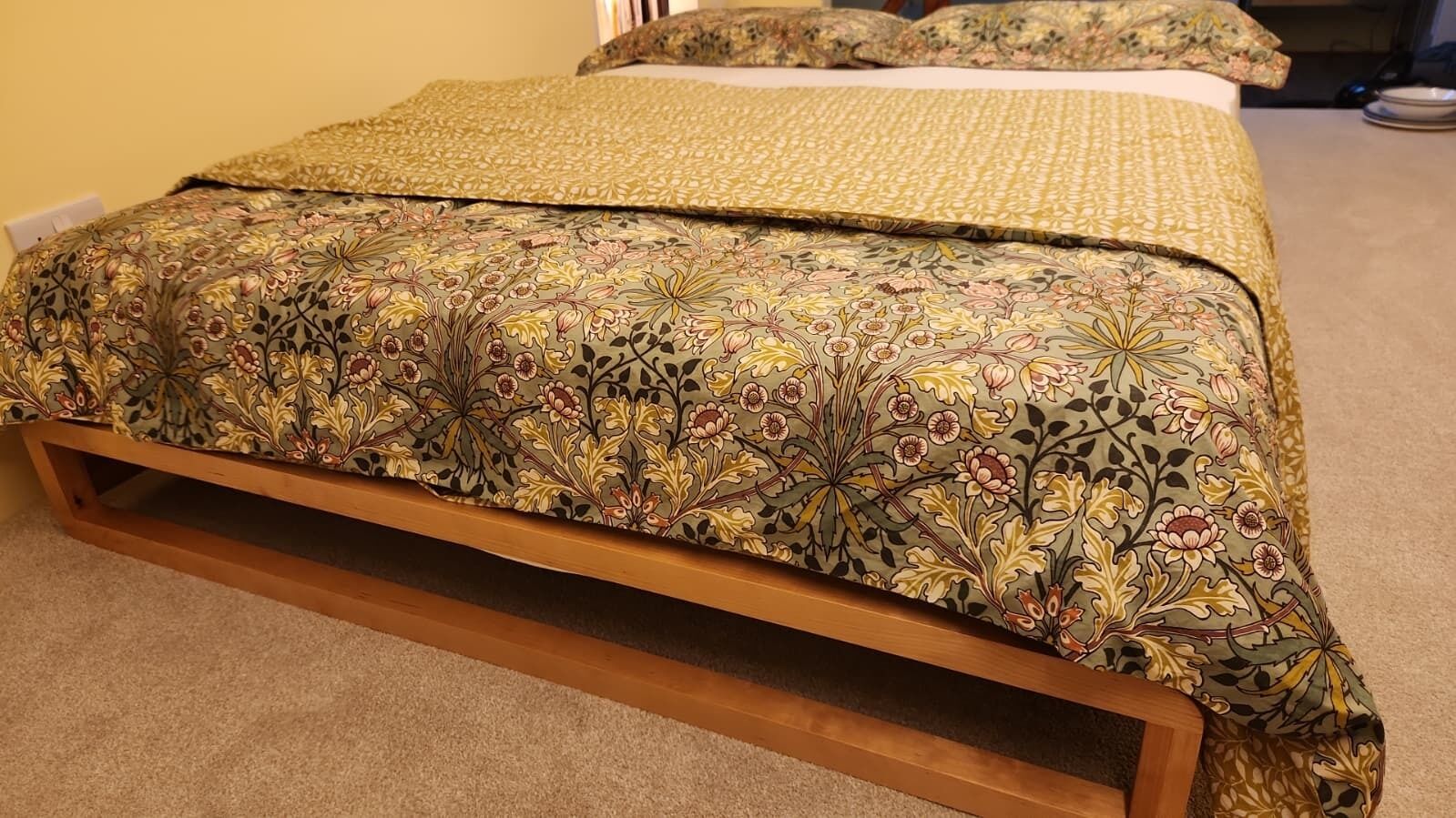 Un lit avec une couvre-lit à motifs floraux et une tête de lit en bois.