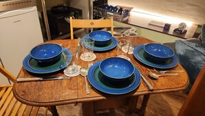 A wooden dining table set with blue plates, silverware, and clear glasses.