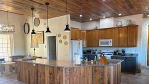 Cuina amb armaris de fusta, una illa de granit i electrodomèstics moderns.