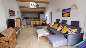 A cozy living room with a grey sofa, a wooden coffee table, and a dining area with a table and chairs. - Quiet - Charming - Atypical - View Luberon - Parc Naturel du Luberon - GR97 (Saint-Saturnin-Lès-Apt)