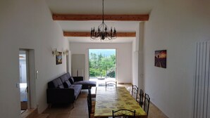 A dining area with a long table and chairs, a sofa, and a chandelier. - Quiet - Charming - Atypical - View Luberon - Parc Naturel du Luberon - GR97 (Saint-Saturnin-Lès-Apt)