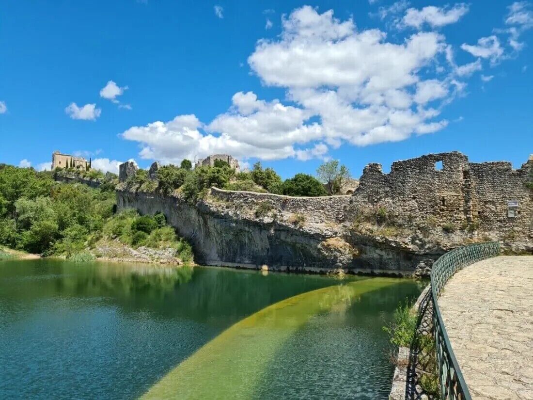 Una estructura de piedra histórica con un río en primer plano y un cielo despejado.