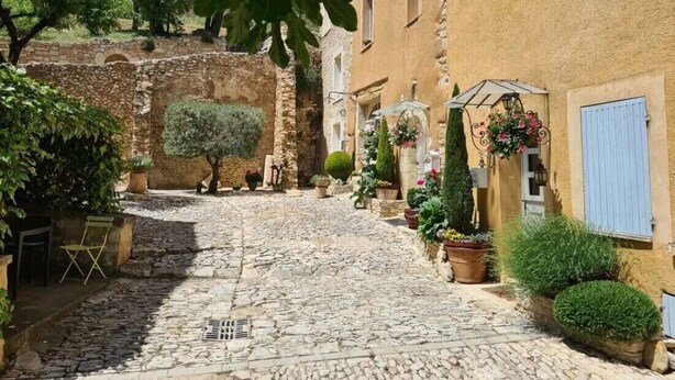 A cobblestone street with stone buildings, potted plants, and a bench. - Quiet - Charming - Atypical - View Luberon - Parc Naturel du Luberon - GR97 (Saint-Saturnin-Lès-Apt)