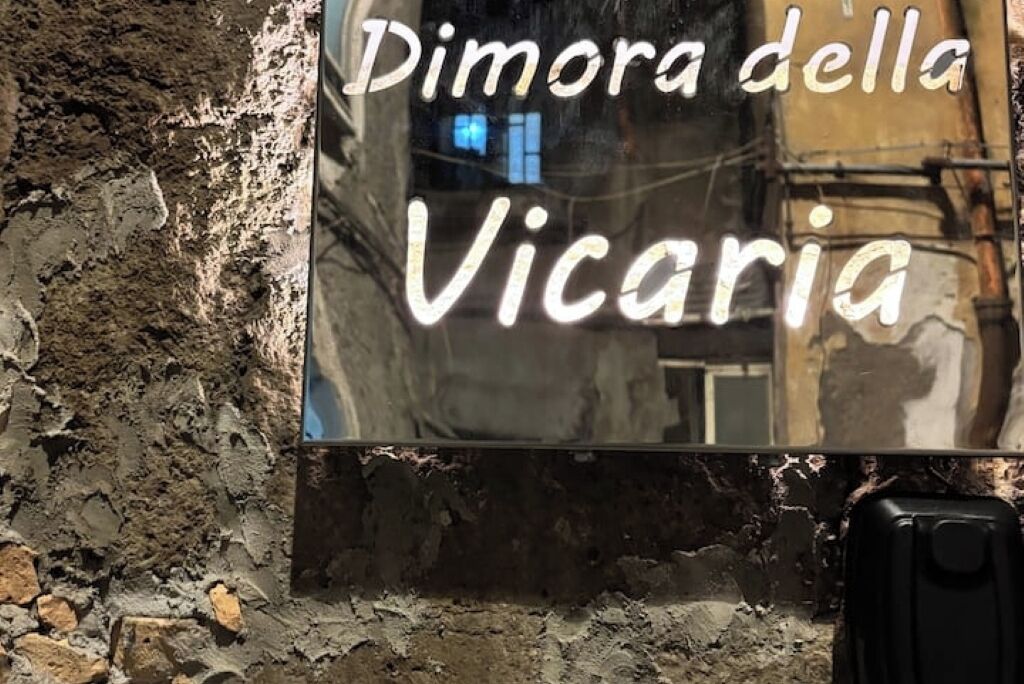 A sign with the text "Dimora della Vicaria" on a wall with a rough texture.