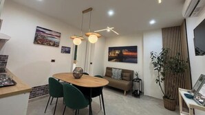 Un espace de salle à manger moderne avec une table ronde, des chaises vertes et des luminaires suspendus.