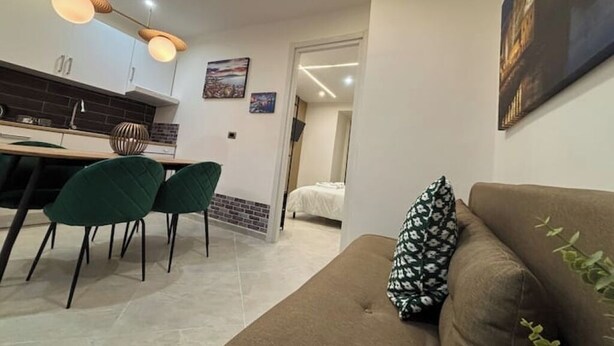 Un salon moderne avec un canapé marron et un coin repas avec des chaises vertes.