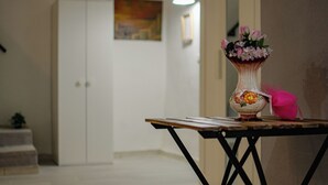 A room with a white door, a painting on the wall, and a table with a vase of flowers. - MIMI HOUSE IN THE HISTORIC CENTRE (Naples)