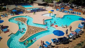A large outdoor swimming pool with multiple lanes, surrounded by lounge chairs and umbrellas. - Luxury Lake Lure Vacation Rental | Sleeps 12+ | Rumbling Bald Resort | Hot Tub (Lake Lure)