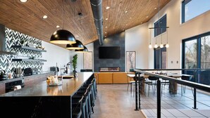 A modern kitchen with a central island, bar stools, pendant lighting, and a large window. - Luxury Lake Lure Vacation Rental | Sleeps 12+ | Rumbling Bald Resort | Hot Tub (Lake Lure)