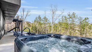 A hot tub with a view of a forest and a staircase leading to a building. - Luxury Lake Lure Vacation Rental | Sleeps 12+ | Rumbling Bald Resort | Hot Tub (Lake Lure)