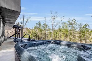 A hot tub with a view of a forest and a staircase leading to a building. - Luxury Lake Lure Vacation Rental | Sleeps 12+ | Rumbling Bald Resort | Hot Tub (Lake Lure)