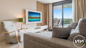 A modern living room with a flat-screen TV, a sofa, a chair, and a dining area with a table and chairs. - Calanova Escape | terrace - pool - golf (La Cala de Mijas)