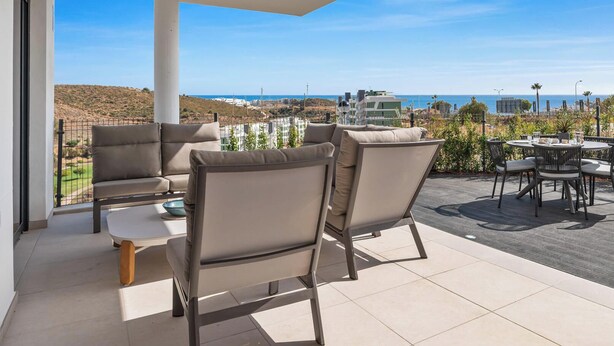 A terrace with outdoor seating, a clear view of the sea, and a modern building in the background. - Calanova Escape | terrace - pool - golf (La Cala de Mijas)