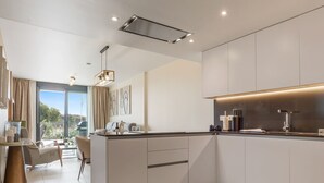 A modern kitchen with a central island, built-in appliances, and a dining area with a view.