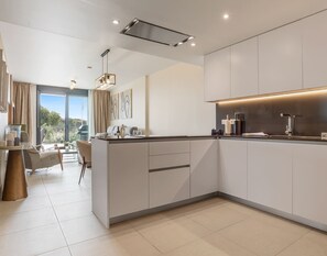 A modern kitchen with a central island, built-in appliances, and a dining area with a view.