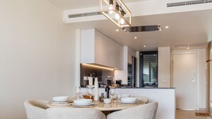 A modern dining area with a round table, four chairs, and a kitchen in the background.