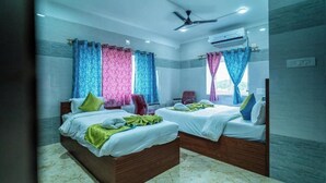 Ein Hotelzimmer mit zwei Betten, einem Deckenventilator, einer Klimaanlage und Blick ins Freie.