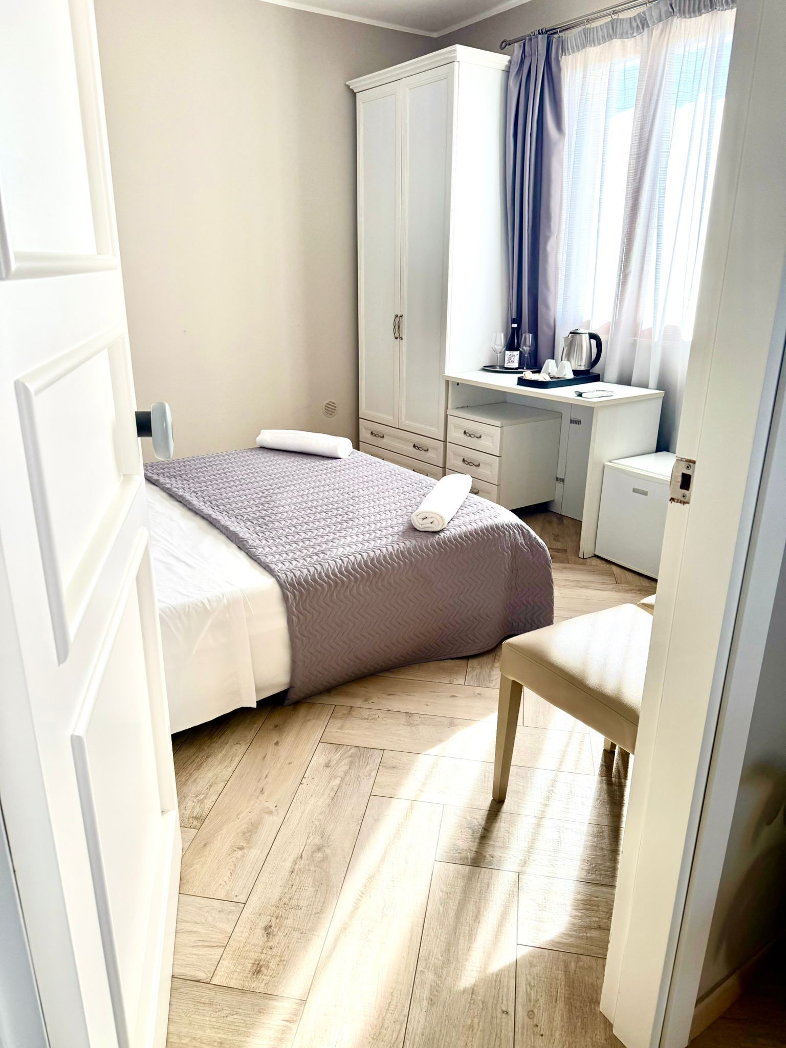 A bedroom with a bed, a desk, a chair, and a wardrobe.