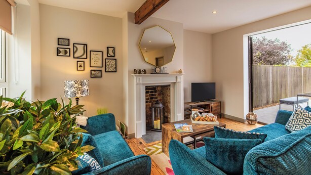 Un salón con chimenea, muebles azules y un espejo grande.