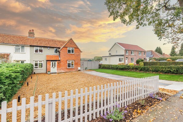 Een woonwijk met huizen, een witte picket fence en een verzorgd gazon.