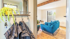Una sala de estar moderna con un sofá azul, piso de madera y un ventanal grande.