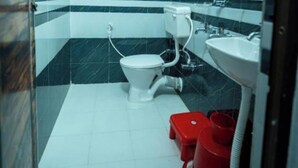 A bathroom with a white toilet, a red bidet, and a white sink.