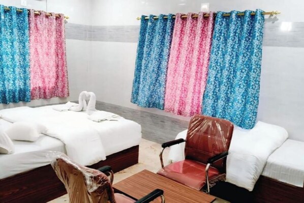 A room with two beds, a wooden table, and a red chair.