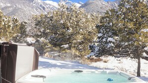 A hot tub in a snowy outdoor setting with mountains in the background.