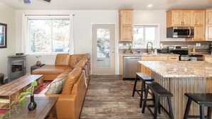 A modern kitchen with wooden cabinets, a built-in microwave, and a large island with stools.
