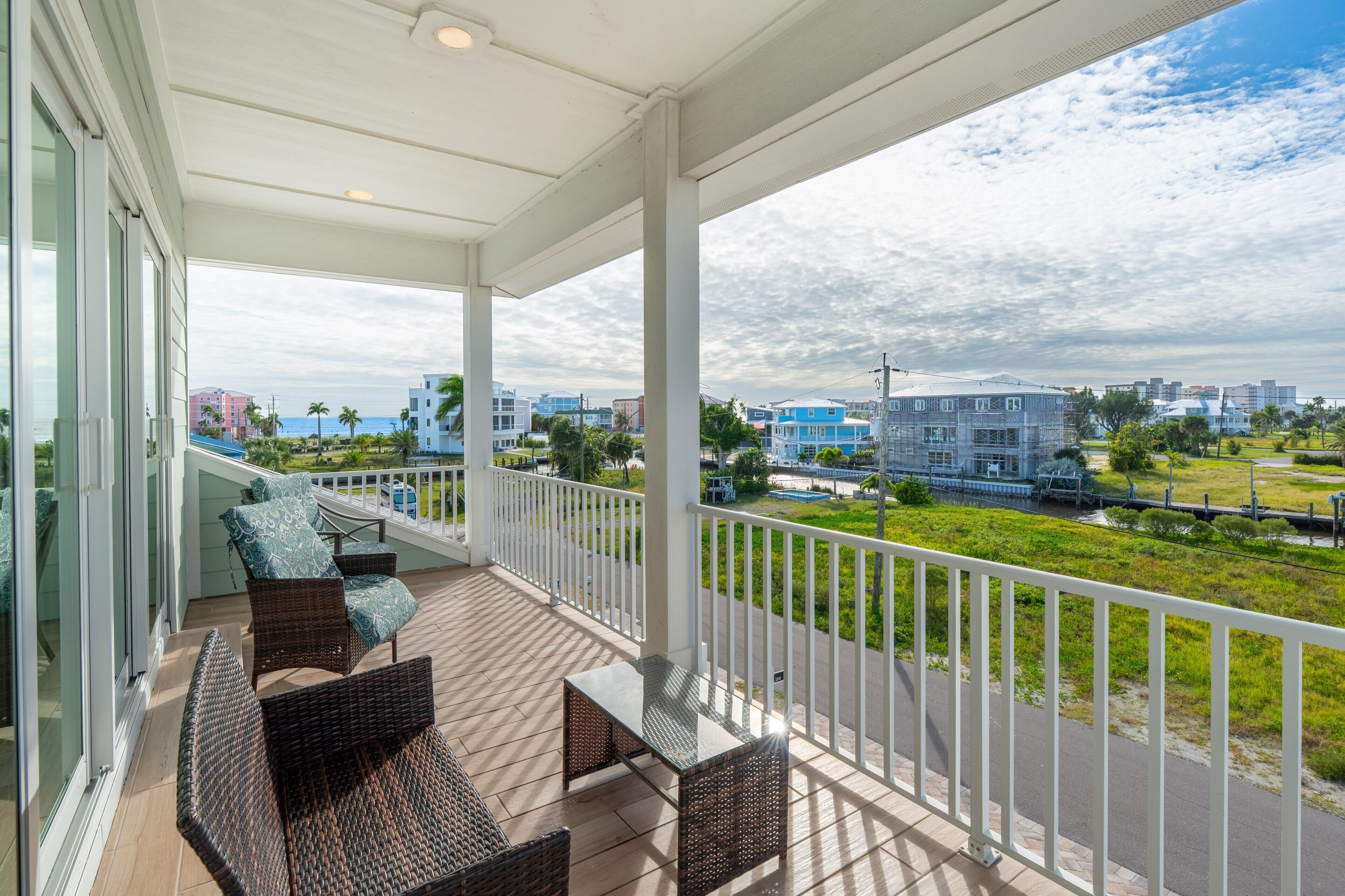 A covered balcony with wicker furniture and a view of the cityscape.