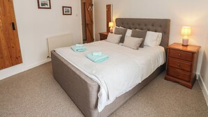 Une chambre à coucher avec un grand lit, une armoire en bois, une table de chevet avec une lampe et un radiateur.