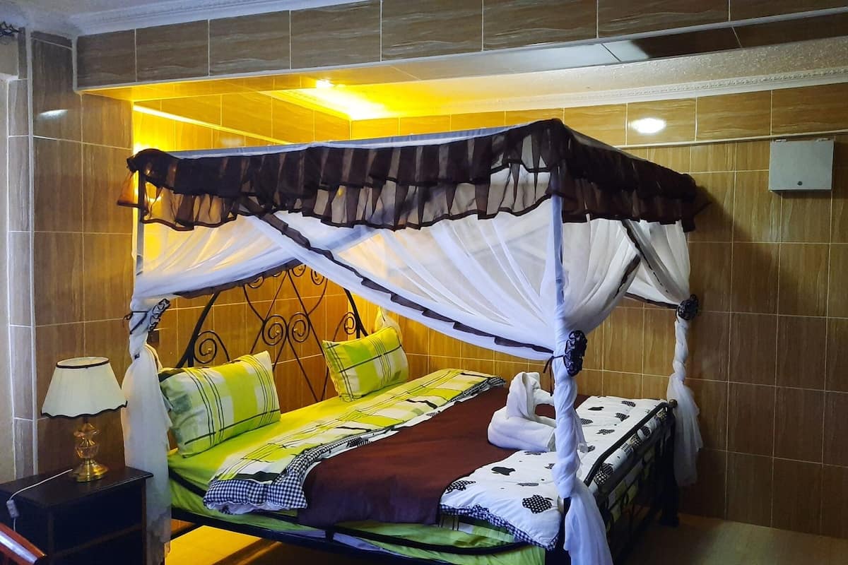 Una cama con dosel, ropa de cama verde y amarilla, y una manta marrón.