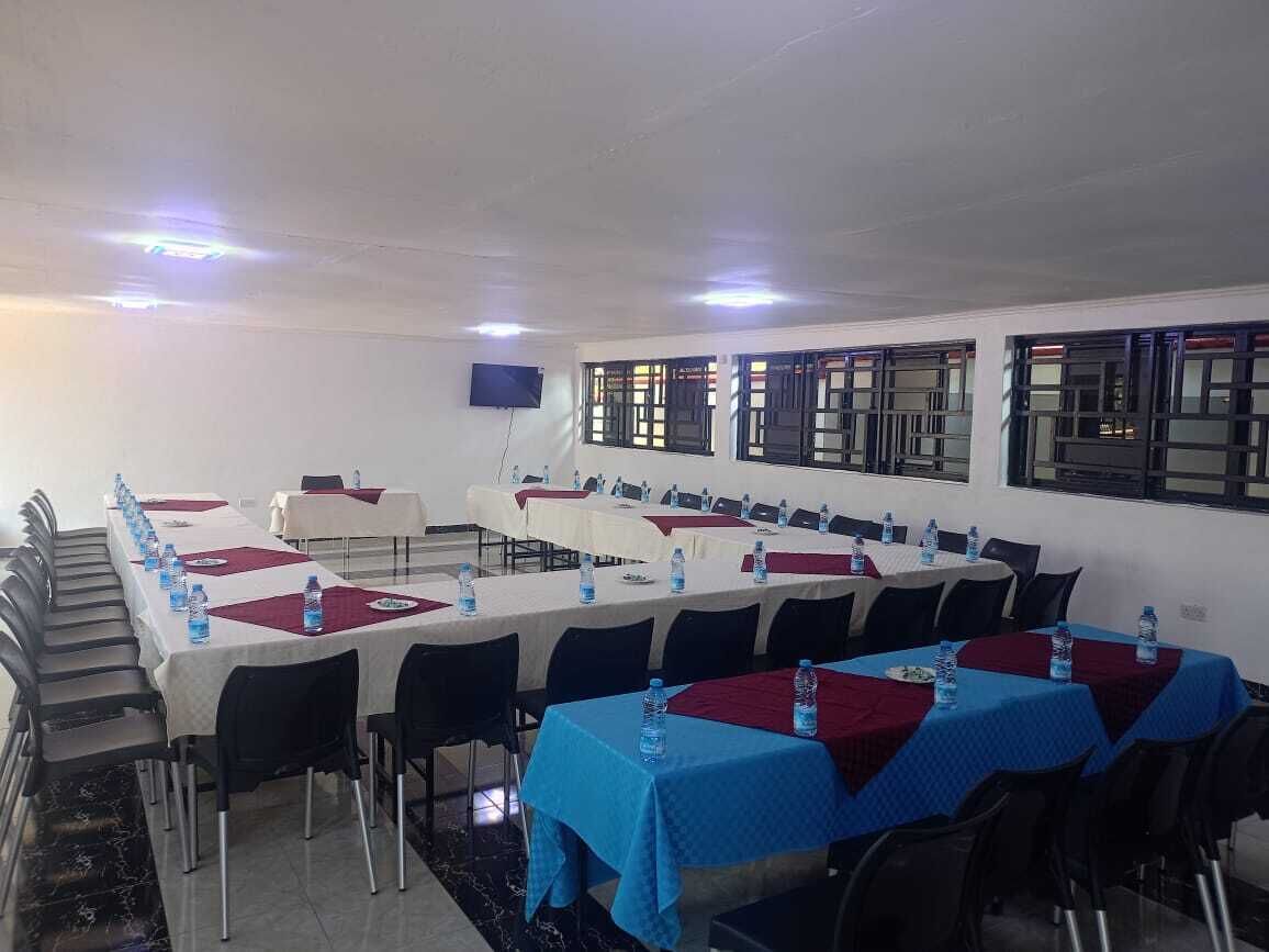 Une salle de conférence équipée de plusieurs tables, de chaises et de bouteilles d’eau.