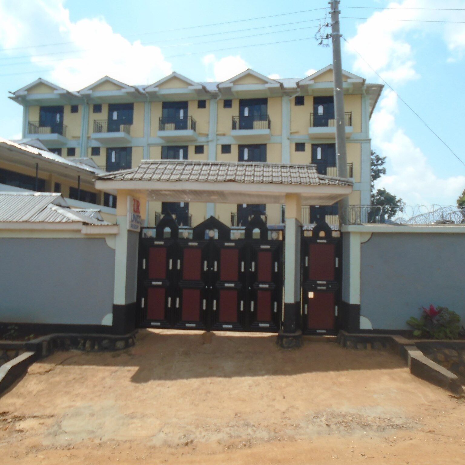 A multi-story building with a gated entrance, a tiled roof, and a visible power line.