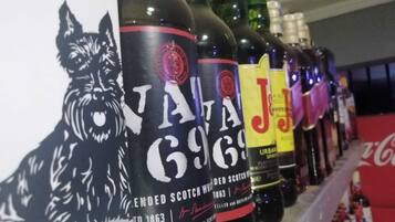 A row of whisky bottles with labels, including one with a cat illustration and another with a red and black label.