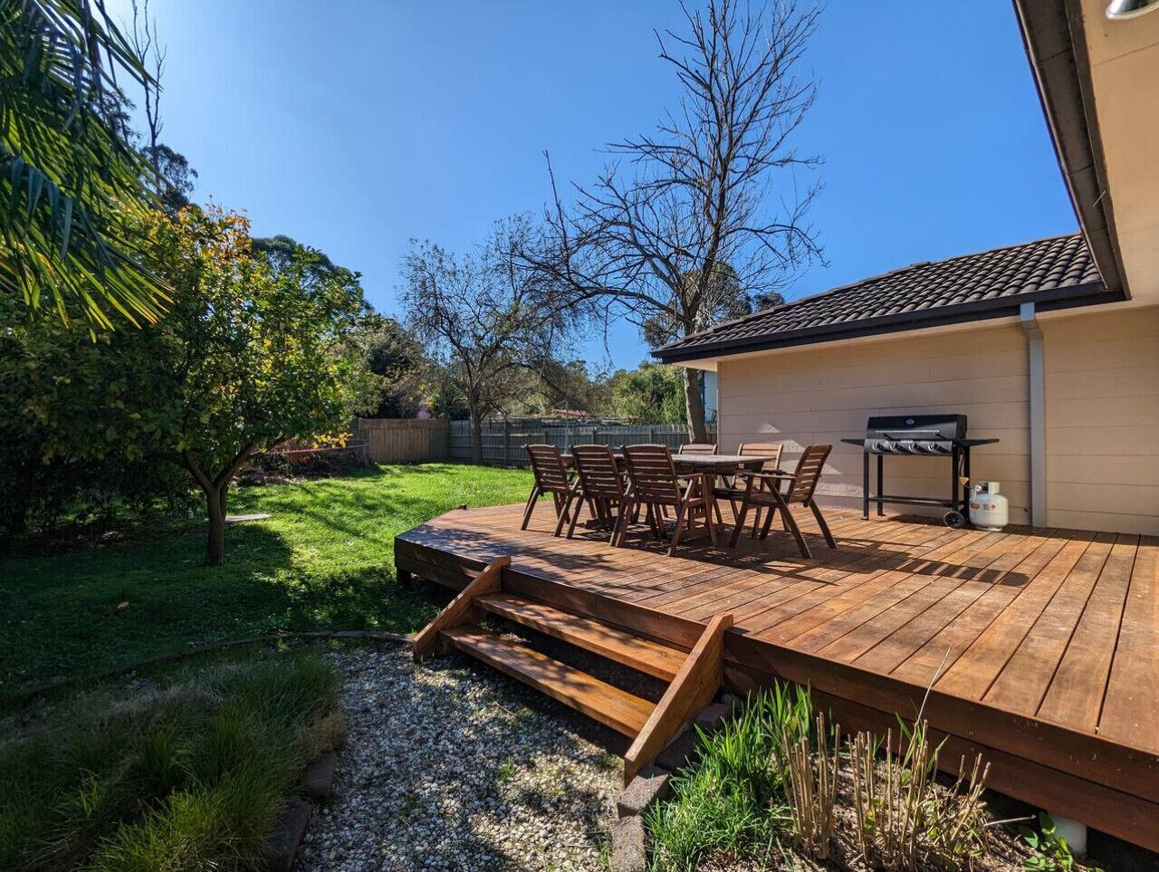 A wooden deck with outdoor furniture, a barbecue grill, and a gas tank.