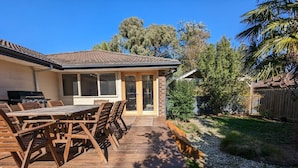 A patio with wooden furniture, a grill, and a view of the backyard. - Sandy`s Retreat- wineries, sanctuary, pets,main st (Healesville)