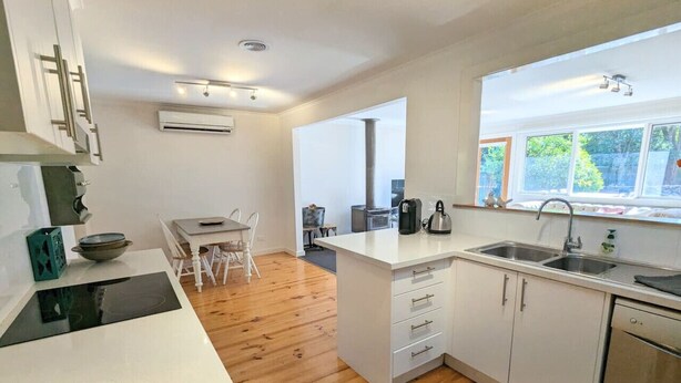 A modern kitchen with white cabinets, a stainless steel sink, and a wooden floor. - Sandy`s Retreat- wineries, sanctuary, pets,main st (Healesville)
