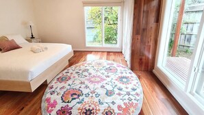 Un dormitorio con cama, un tapete redondo, una ventana y una puerta.