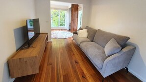 Una sala de estar moderna con un sofá gris, una mesa de centro de madera y un televisor de pantalla plana.