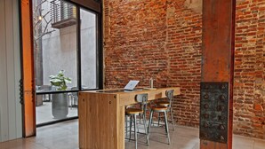 A modern bar area with a wooden counter, metal stools, and a large window.