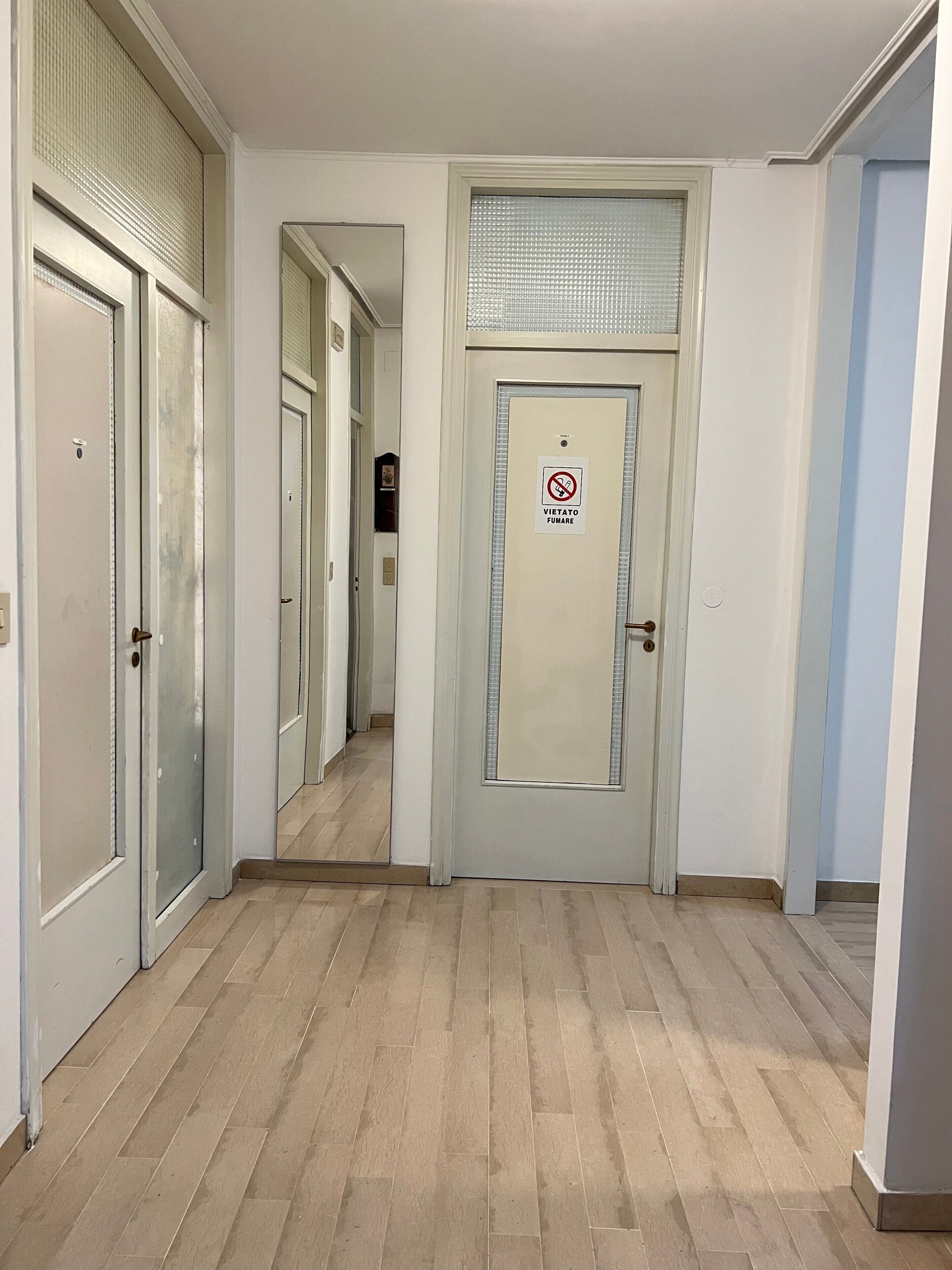 A hallway with a door marked 'Vietato Fumare' (No Smoking).