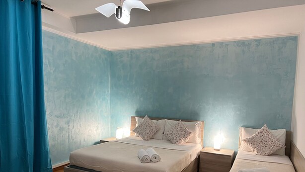 A bedroom with two beds, a nightstand, a ceiling fan, and a blue curtain. - 'Venice' Apartment with Wi-Fi and Air Conditioning (Venezia)